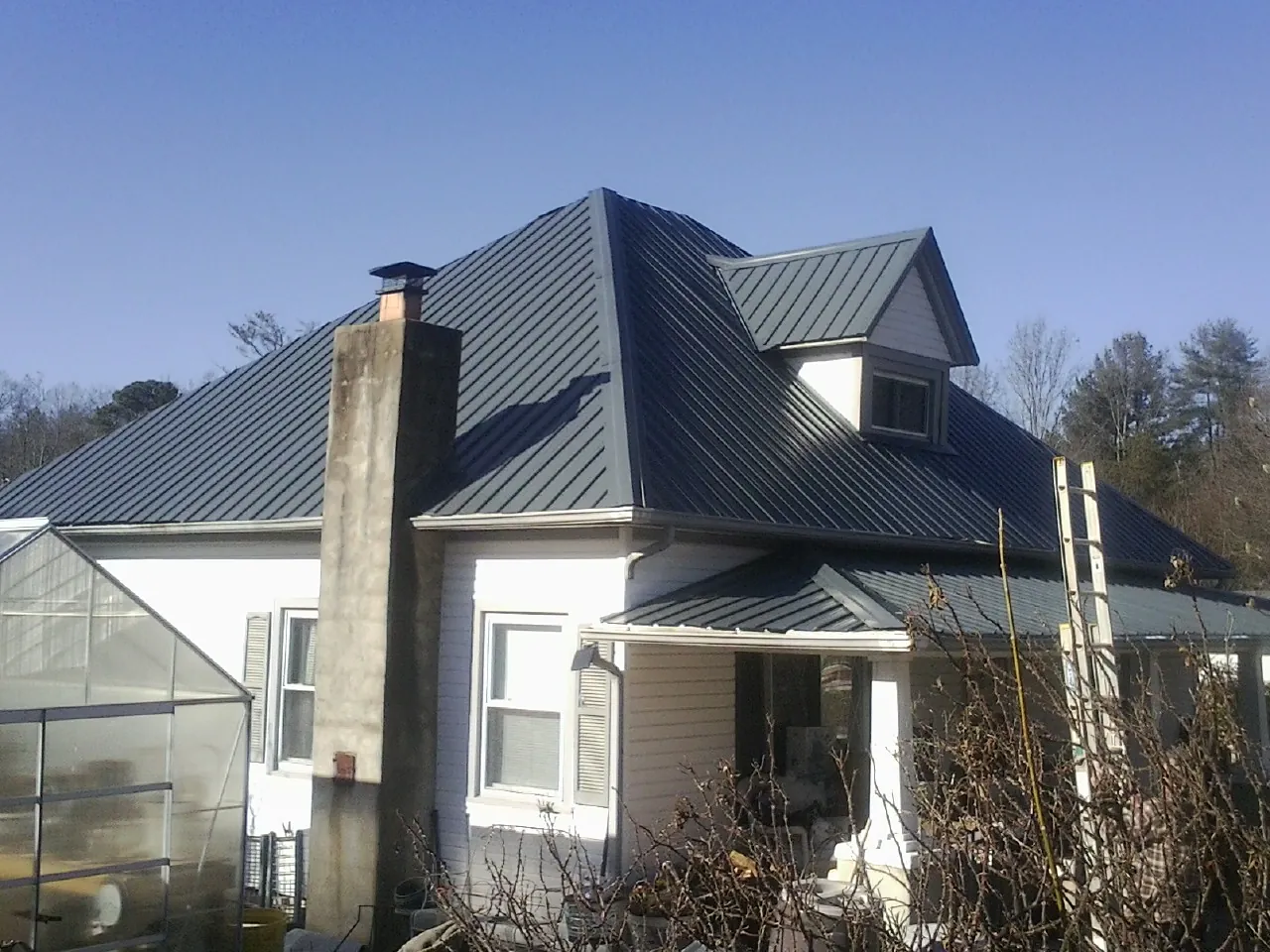 Dark blue standing seam metal roof on a white farmhouse with dormer — Slate & Tile Roof Repair by Roofing Brothers in San Geronimo