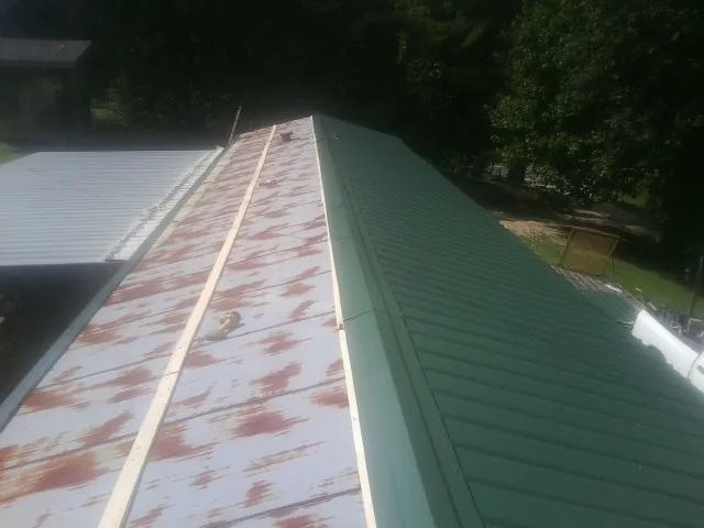 Old rusted panels beside newly installed green metal roofing — Wind Damage Roof Repair by Roofing Brothers in San Geronimo