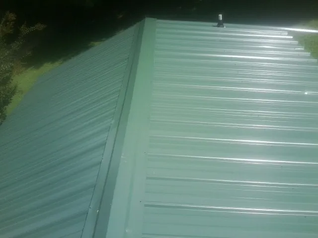 New green metal panels meeting at the ridge of a roof — Flat Roof Repair work by our crew in San Geronimo