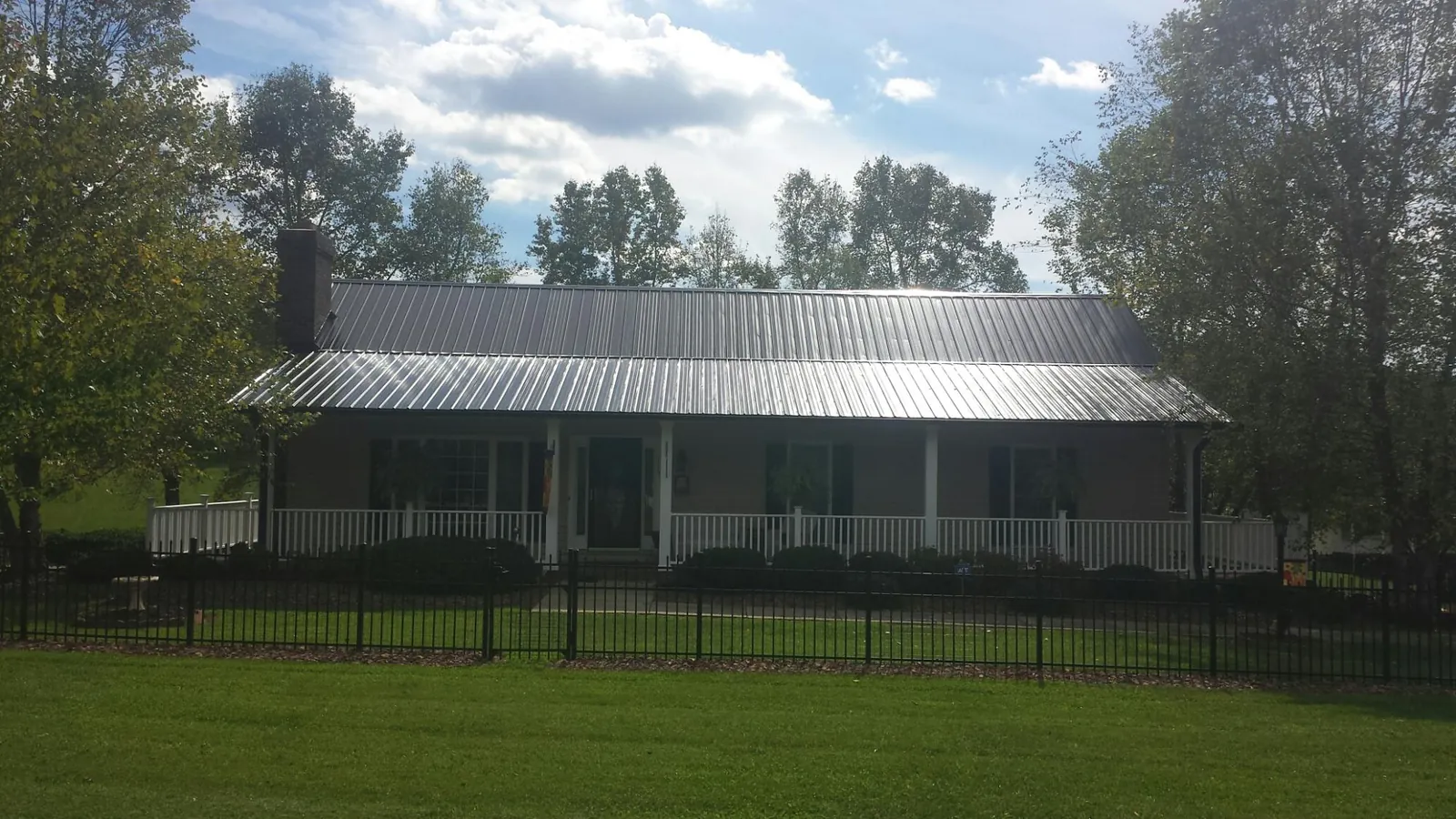 Gray metal roof on a brick ranch with a full width front porch — Gutter Guard Installation work by our crew in San Geronimo