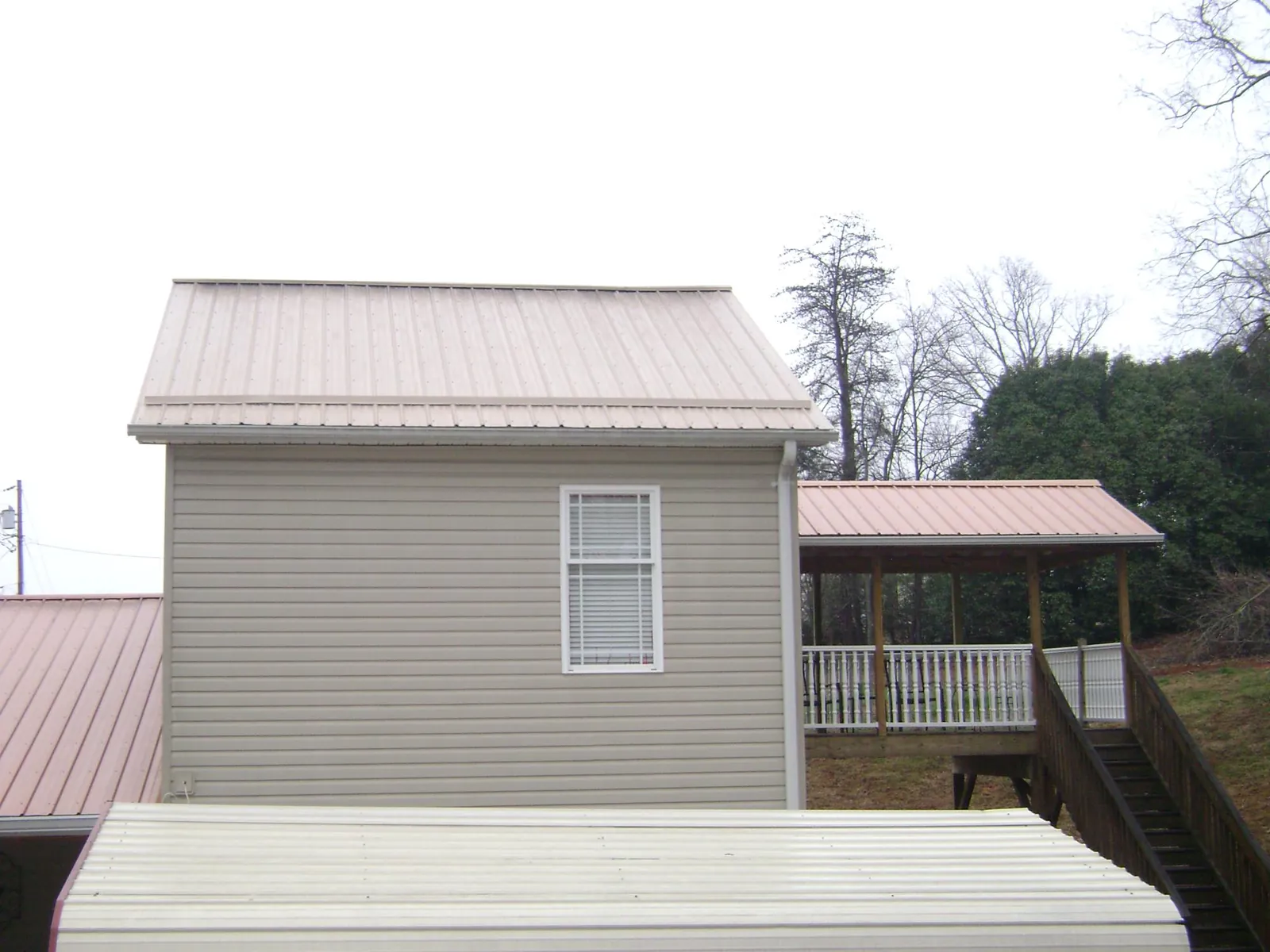 Tan metal roofs on a two story addition and attached porch, from a Roof Replacement job in San Geronimo